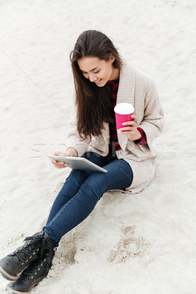 Caucasian lady sitting outdoors at beach using tablet computer Stock photo © deandrobot