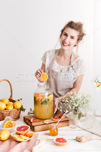 Happy woman standing indoors cooking citrus beverage Stock photo © deandrobot