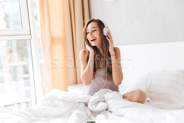 Carefree lady in pajamas listening music with headphones Stock photo © deandrobot