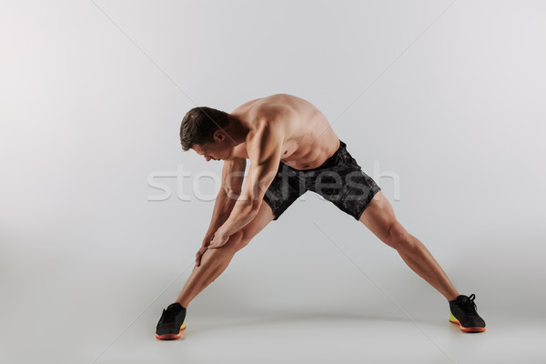 Concentrated young sportsman make stretching exercises Stock photo © deandrobot