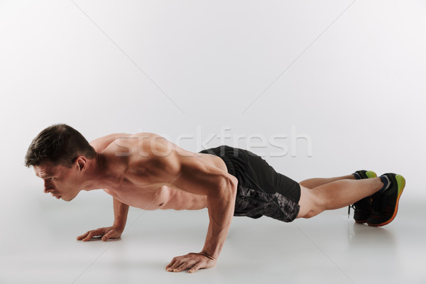 Concentrated young sportsman make sport exercises Stock photo © deandrobot