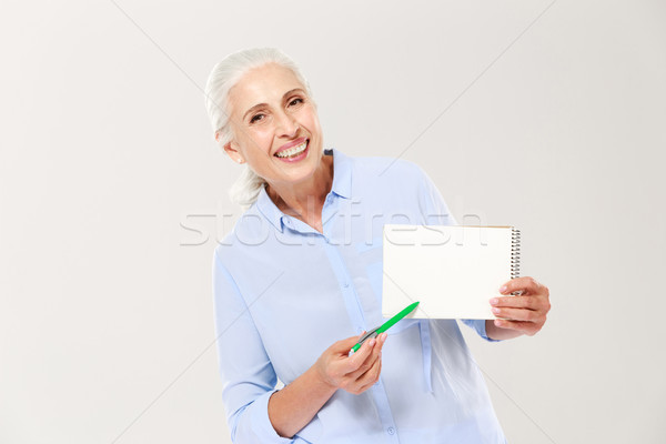 Smiling mature woman showing notebook with copy space for text isolated Stock photo © deandrobot