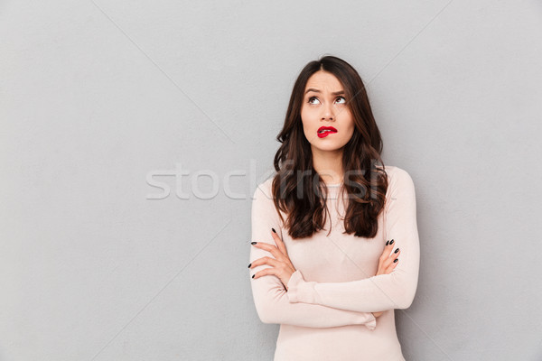 Portrait of young woman biting her red lips standing with arms f Stock photo © deandrobot
