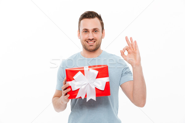 Image of pleased brunette guy smiling and showing OK sign while  Stock photo © deandrobot
