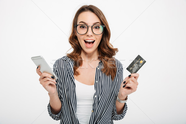 Portrait of a satisfied casual girl holding mobile phone Stock photo © deandrobot