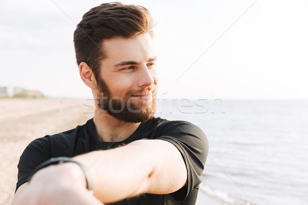 Smiling young sportsman doing stretching exercises Stock photo © deandrobot