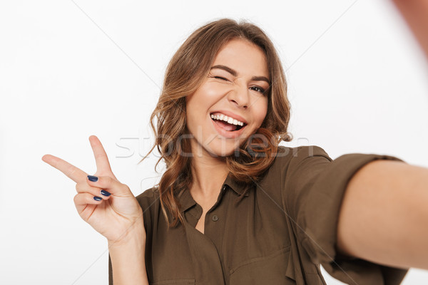 Portrait of a smiling young woman taking selfie Stock photo © deandrobot