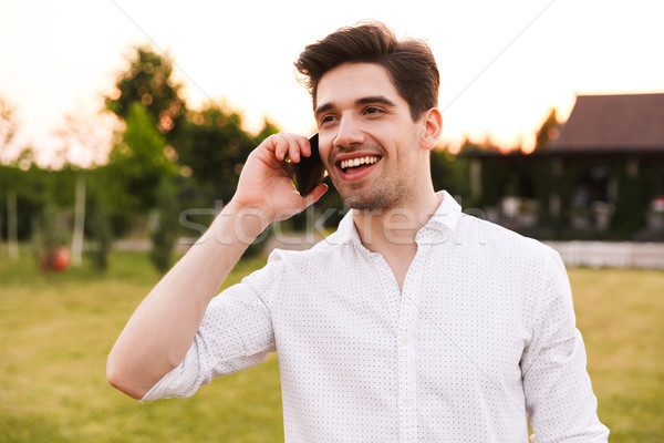 Image of caucasian happy man 25-30 wearing white shirt smiling,  Stock photo © deandrobot