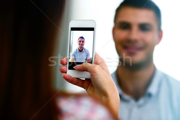 Woman making photo of a man on smartphone. Focus on smartphone Stock photo © deandrobot
