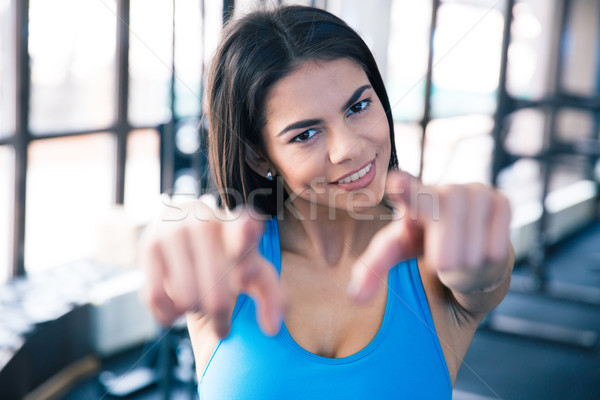 Smiling young woman pointing at camera Stock photo © deandrobot