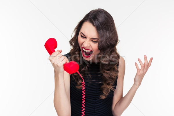 Crazy raged retro styled female shouting in red telephone receiver  Stock photo © deandrobot