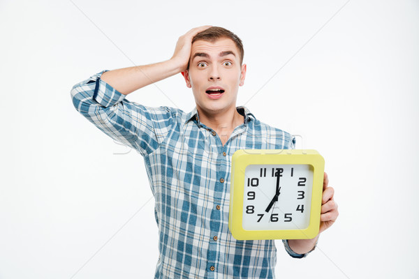 Shocked excited young man holding big clock Stock photo © deandrobot