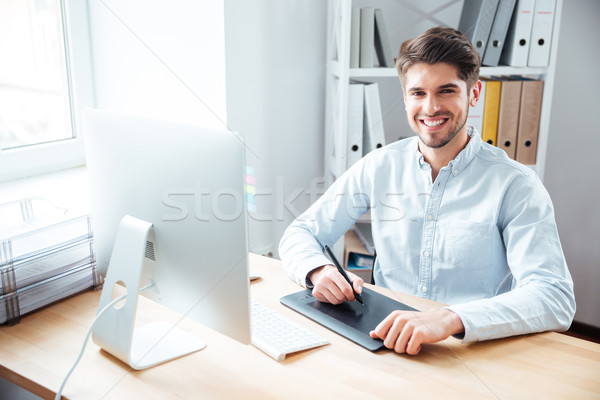 Smiling man designer working and using graphic tablet in office Stock photo © deandrobot
