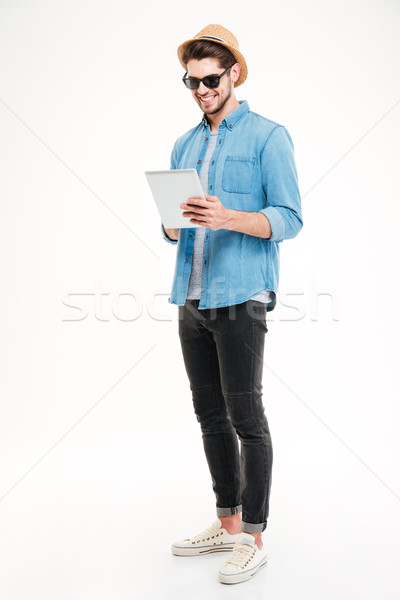 Full length of happy handsome young man using tablet Stock photo © deandrobot