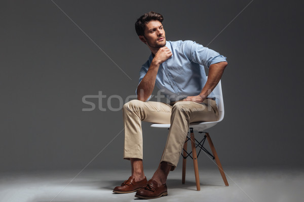 Attractive young brunette man in blue shirt sitting Stock photo © deandrobot