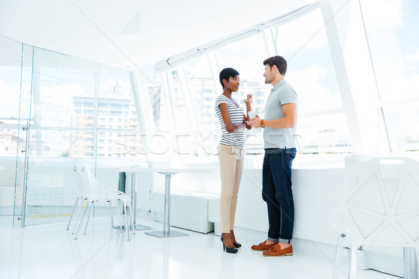 Foto stock: Dos · jóvenes · gente · de · negocios · pie · hablar · oficina