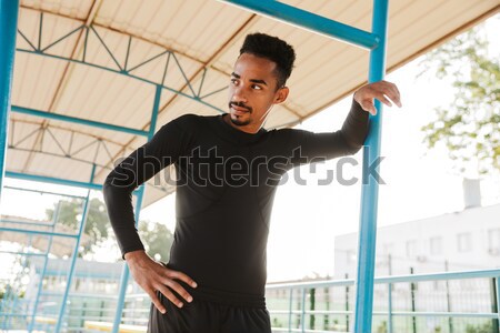 Handsome bearded sportsman in sportswear and wristband standing outdoors Stock photo © deandrobot