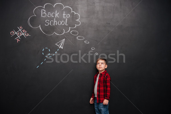 Boy over chalkboard with school drawings while looking on it Stock photo © deandrobot