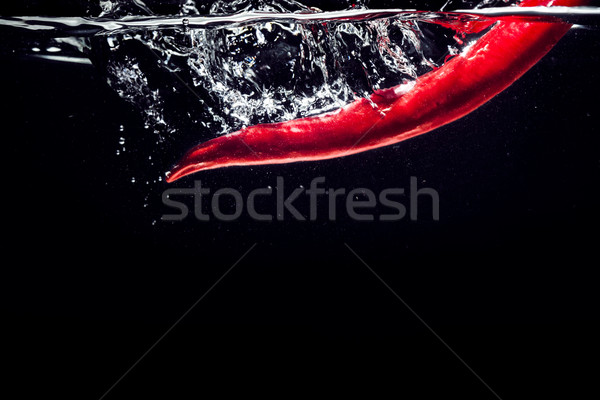 Red chili peppers falling into the water isolated Stock photo © deandrobot