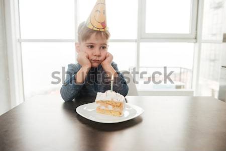 Little birthday boy sitting in kitchen near cake alone Stock photo © deandrobot