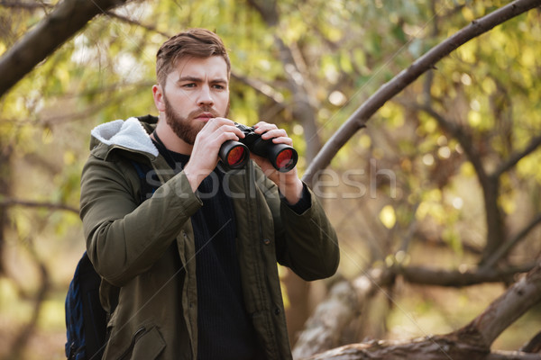 Handsome bearded man holding field-glass in the forest Stock photo © deandrobot