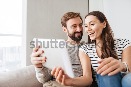 Cheerful loving couple in kitchen indoors using tablet computer Stock photo © deandrobot