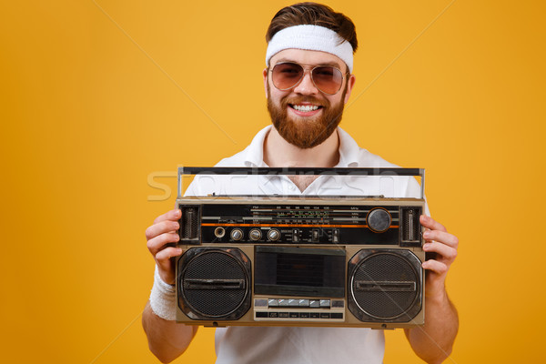 Happy young man wearing sunglasses holding tape recorder Stock photo © deandrobot