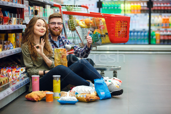 Jóvenes alegre Pareja supermercado comer chips Foto stock © deandrobot