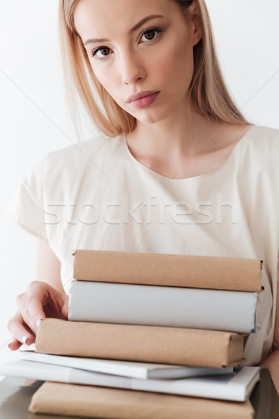Serious blonde woman holding books. Looking at camera. Stock photo © deandrobot