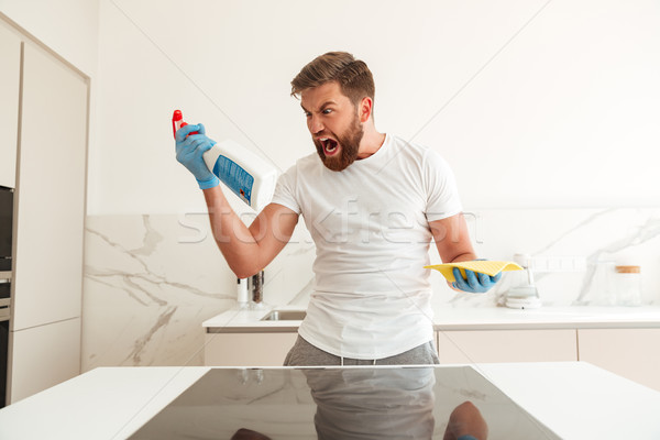 Screaming bearded man with cleaners on kitchen Stock photo © deandrobot