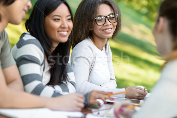 Tineri studenţi şedinţei studiu în aer liber vorbesc Imagine de stoc © deandrobot