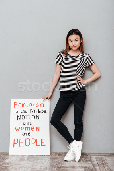 Serious woman holding blank with text about feminism. Stock photo © deandrobot