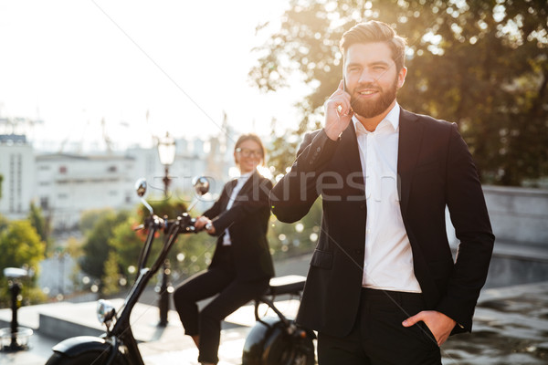 [[stock_photo]]: Heureux · homme · d'affaires · posant · extérieur · parler · smartphone