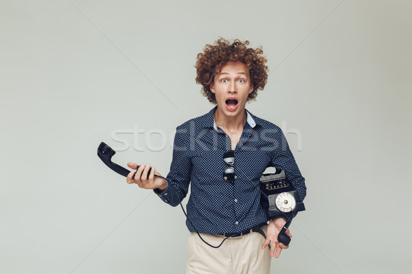 Shocked retro man dressed in shirt with telephone in hands. Stock photo © deandrobot