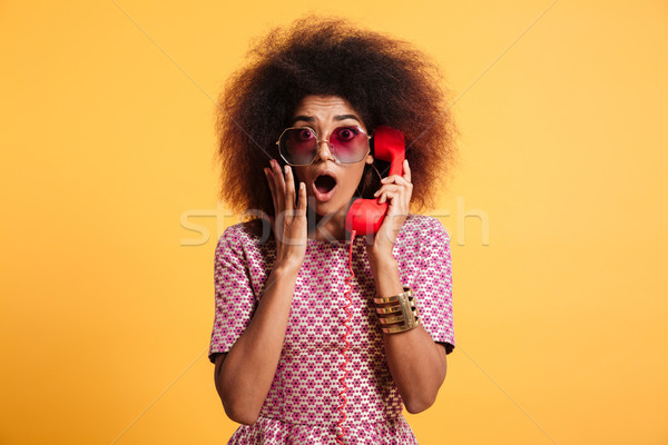 Close-up photo of shocked retro girl with afro hairstyle holding Stock photo © deandrobot