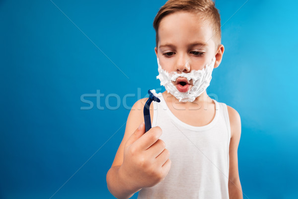 Surprised young boy in shaving foam looking at razor Stock photo © deandrobot