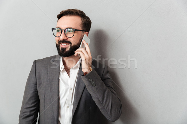 Handsome businesslike man in formal wear having mobile conversat Stock photo © deandrobot