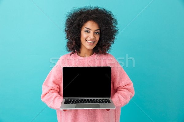 Portrait of cheerful woman 20s holding laptop and demonstrating  Stock photo © deandrobot