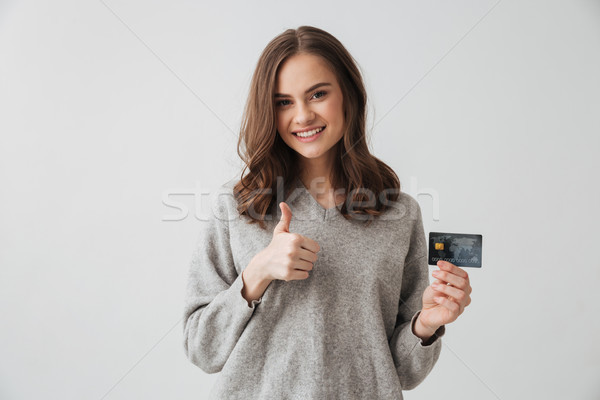 Smiling brunette woman in sweater holding credit card Stock photo © deandrobot
