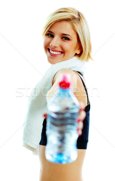 Young cheerful fit woman passing a bottle of water to you Stock photo © deandrobot