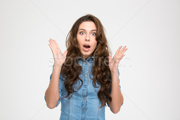 Shocked amazed young woman with raised hands and opened mouth  Stock photo © deandrobot