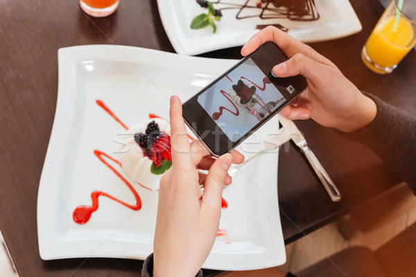 Woman hands taking pictures of dessert on plate using smartphone Stock photo © deandrobot