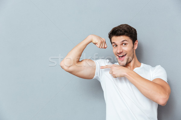 Mosolyog férfi mutat bicepsz derűs lezser Stock fotó © deandrobot