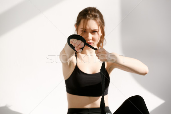 Serious woman is wrapping hands with black boxing bandage Stock photo © deandrobot
