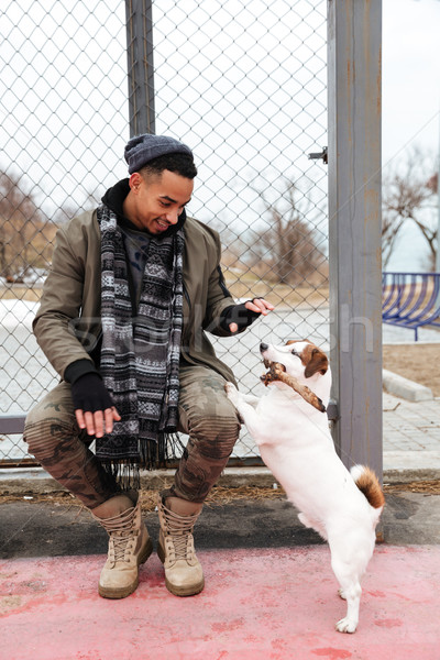 Stock photo: Young african man wearing hat and scarf walking with dog.