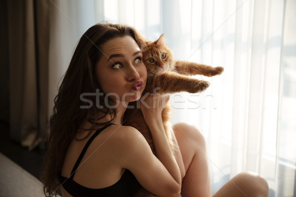 Amusing woman holding cat and making funny face at home Stock photo © deandrobot