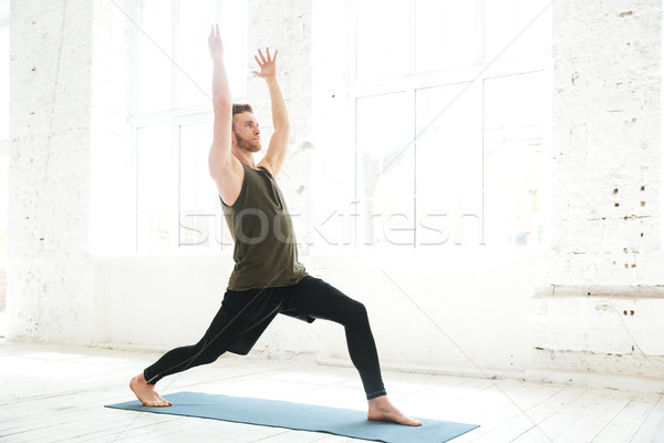 Concentrated young man parctising yoga pose on a fitness mat Stock photo © deandrobot