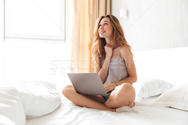 Młodych piękna kobieta posiedzenia bed laptop czeka Zdjęcia stock © deandrobot