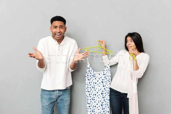 Young displeased man standing near woman with dresses Stock photo © deandrobot