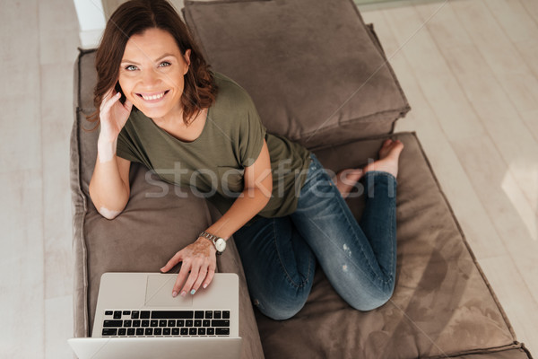 Top view of smiling casual sitting on sofa with computer Stock photo © deandrobot